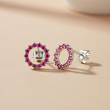 Silversmiths sterling silver stud earrings with simulated ruby circles rest on a beige surface.