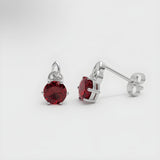 Sterling silver Celtic stud earrings with simulated ruby stones and a white background.