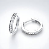 Silversmiths sterling silver pavé cubic zirconia huggie hoops with clear stones in front, displayed on a white surface.