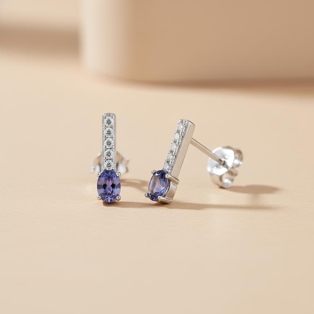 Sterling silver drop studs with vertical cubic zirconia and simulated tanzanite shown on a beige surface.