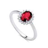 Sterling silver ring by Silversmiths featuring an oval simulated ruby and clear stones in a halo cluster setting.