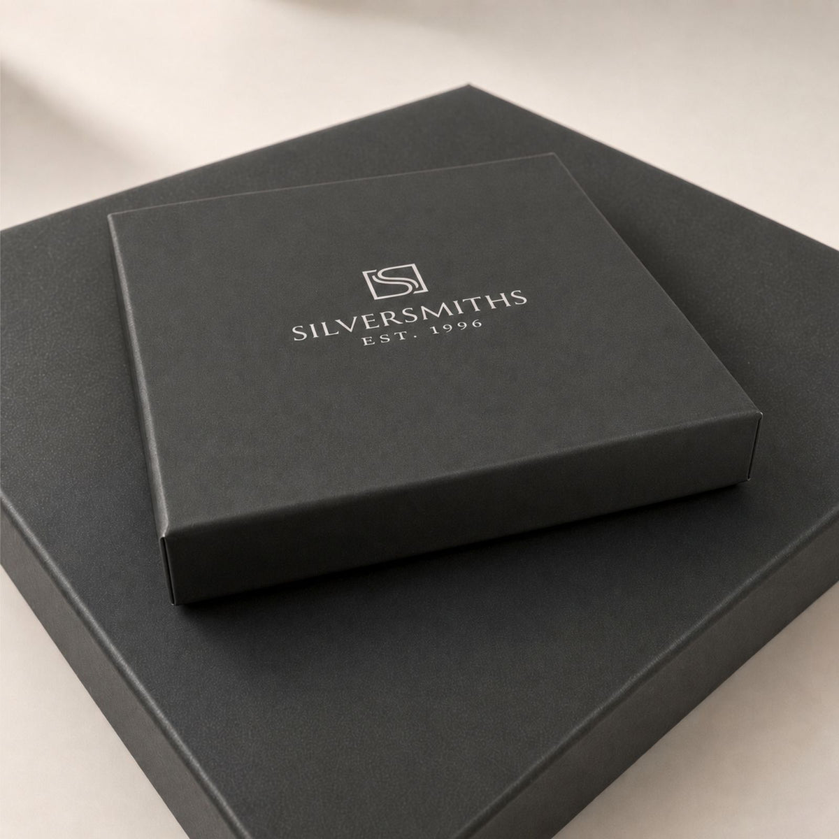 A black box labeled “SILVERSMITHS EST. 1996” with a silver logo sits on top of another sleek black box.