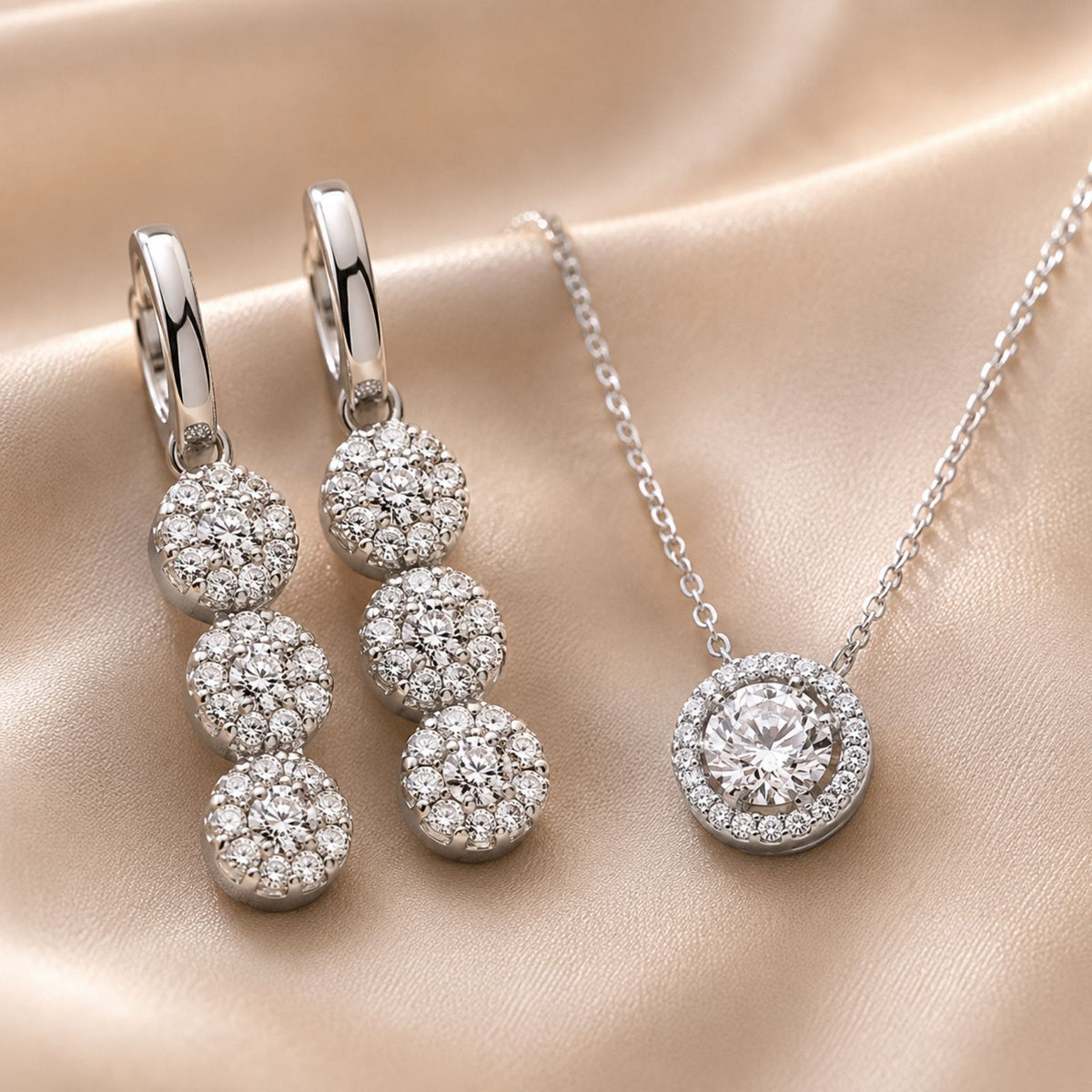 Silver drop earrings feature three interlocking circles, paired with a round pendant necklace set with clear gemstones.
